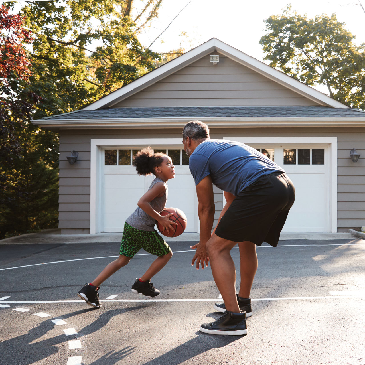 basketball-family-house father and daughter play basketball on their driveway at home