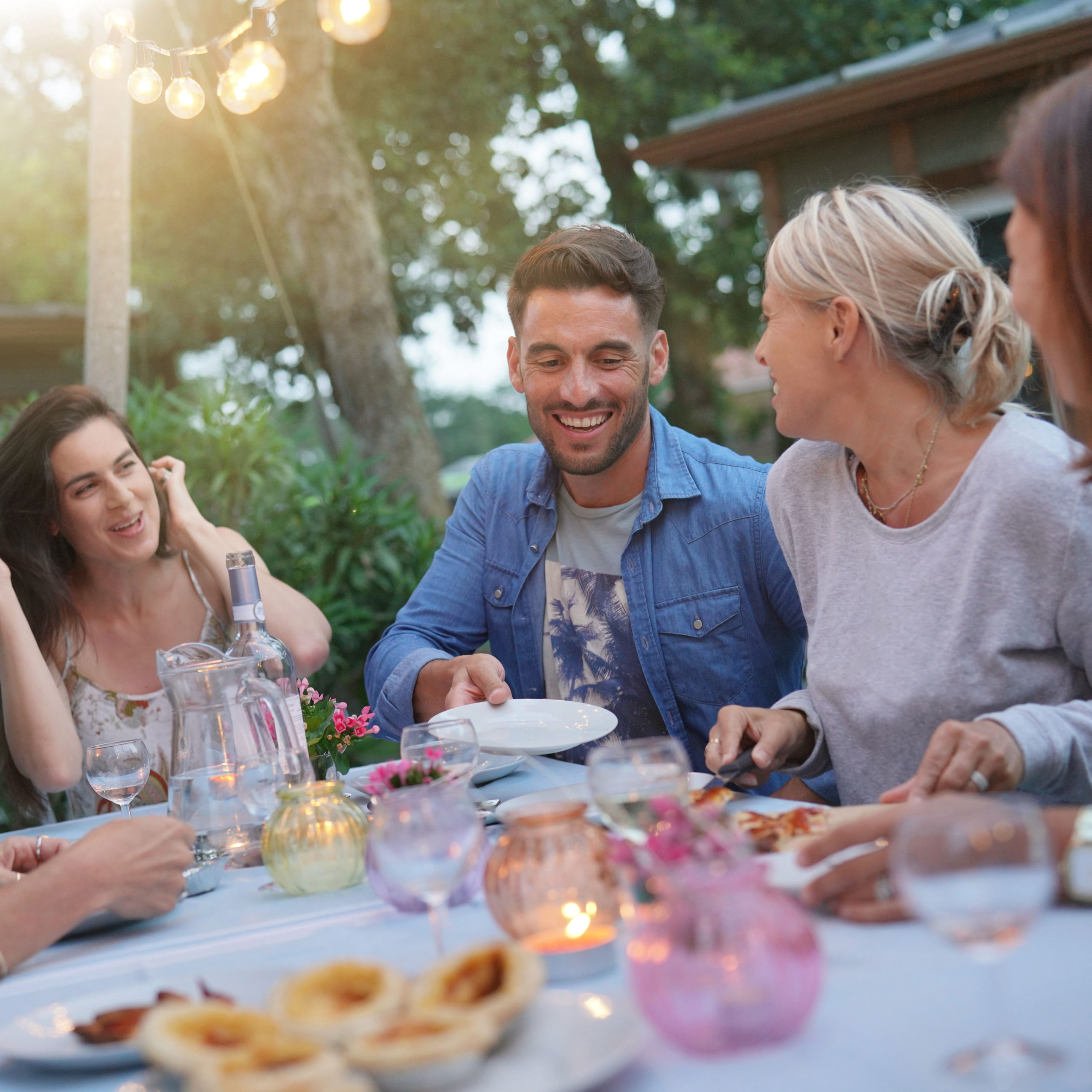 Friends enjoying summer barbecue dinner in garden